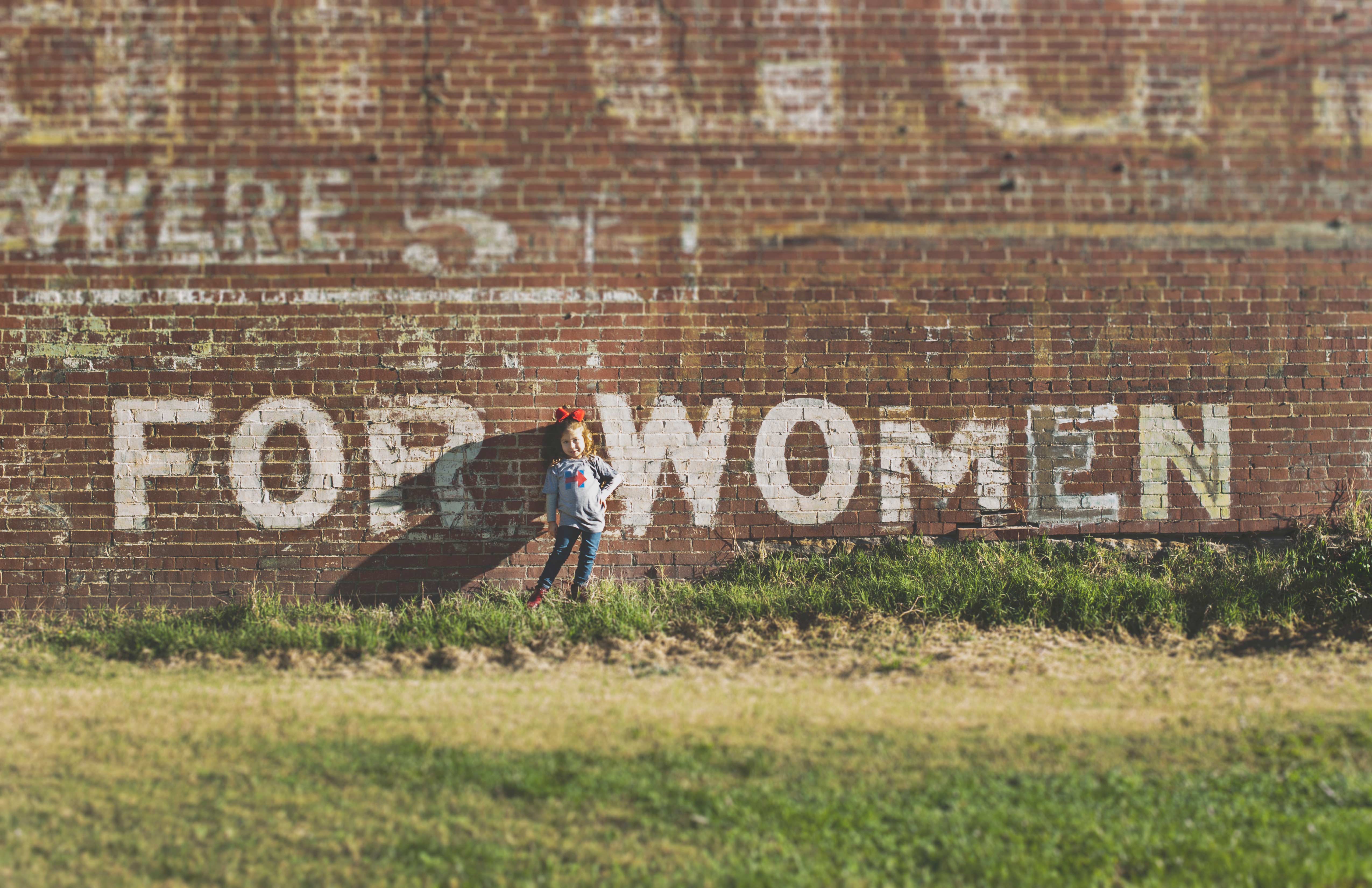 Little girl standing in front of brick building