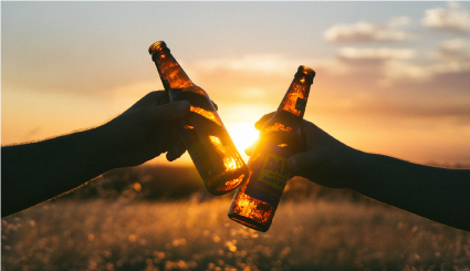 Two people saying "cheers" and clinking together glass bottles