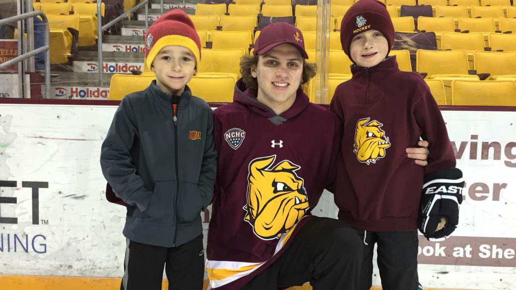 kids posing with UMD hockey player at skate with the bulldogs
