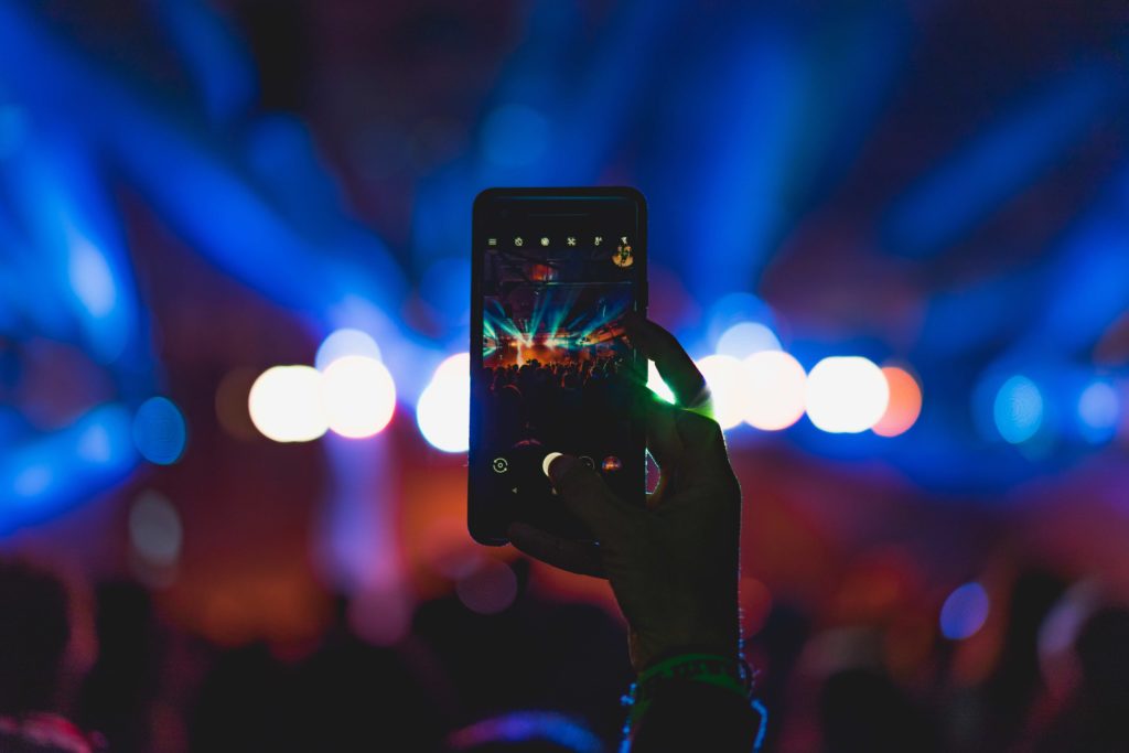 person taking a video at a concert with their phone