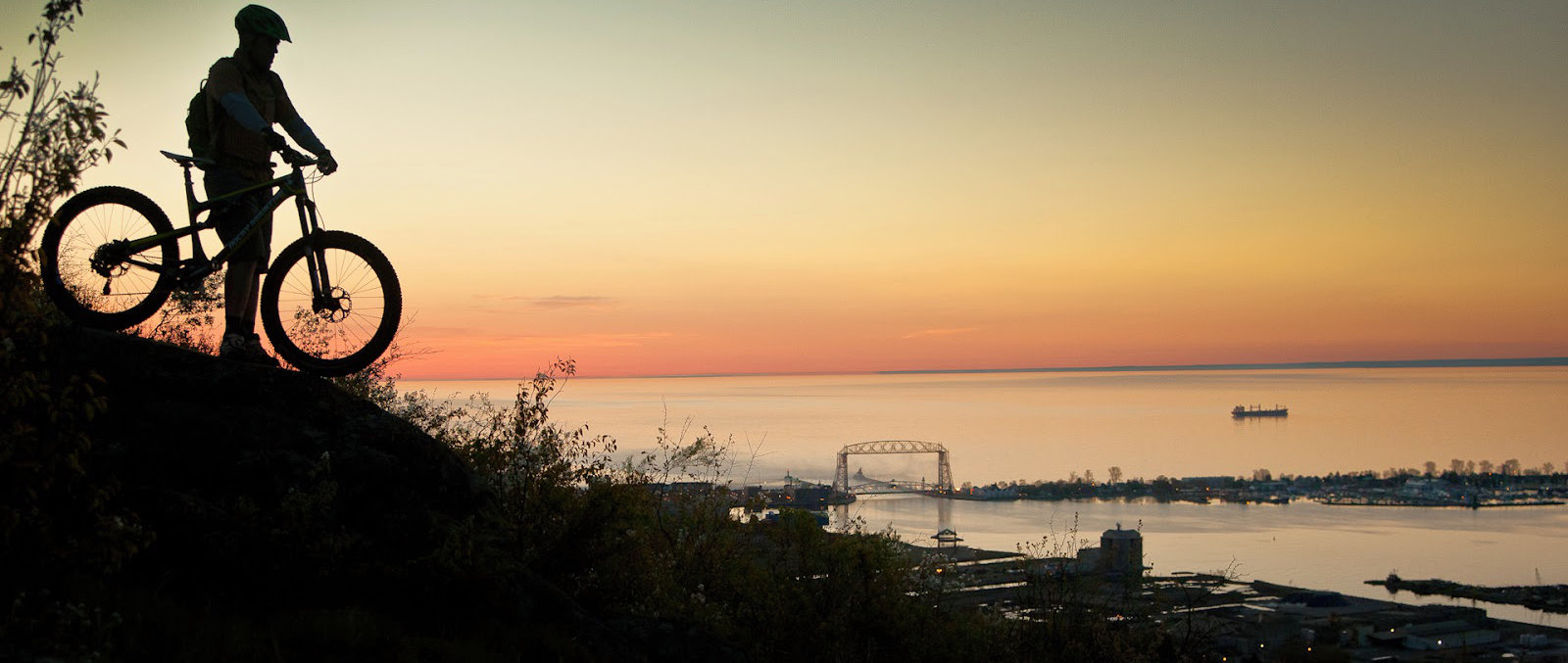 Person on their bike looking over Lake Superior at sunset