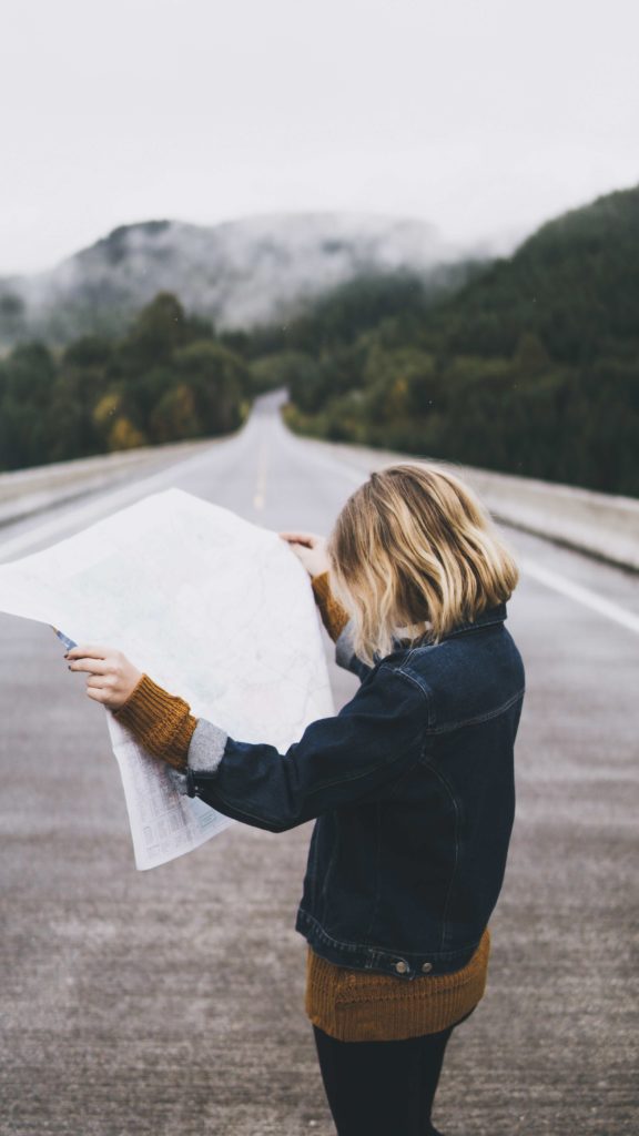 Woman standing in the road looking at a map